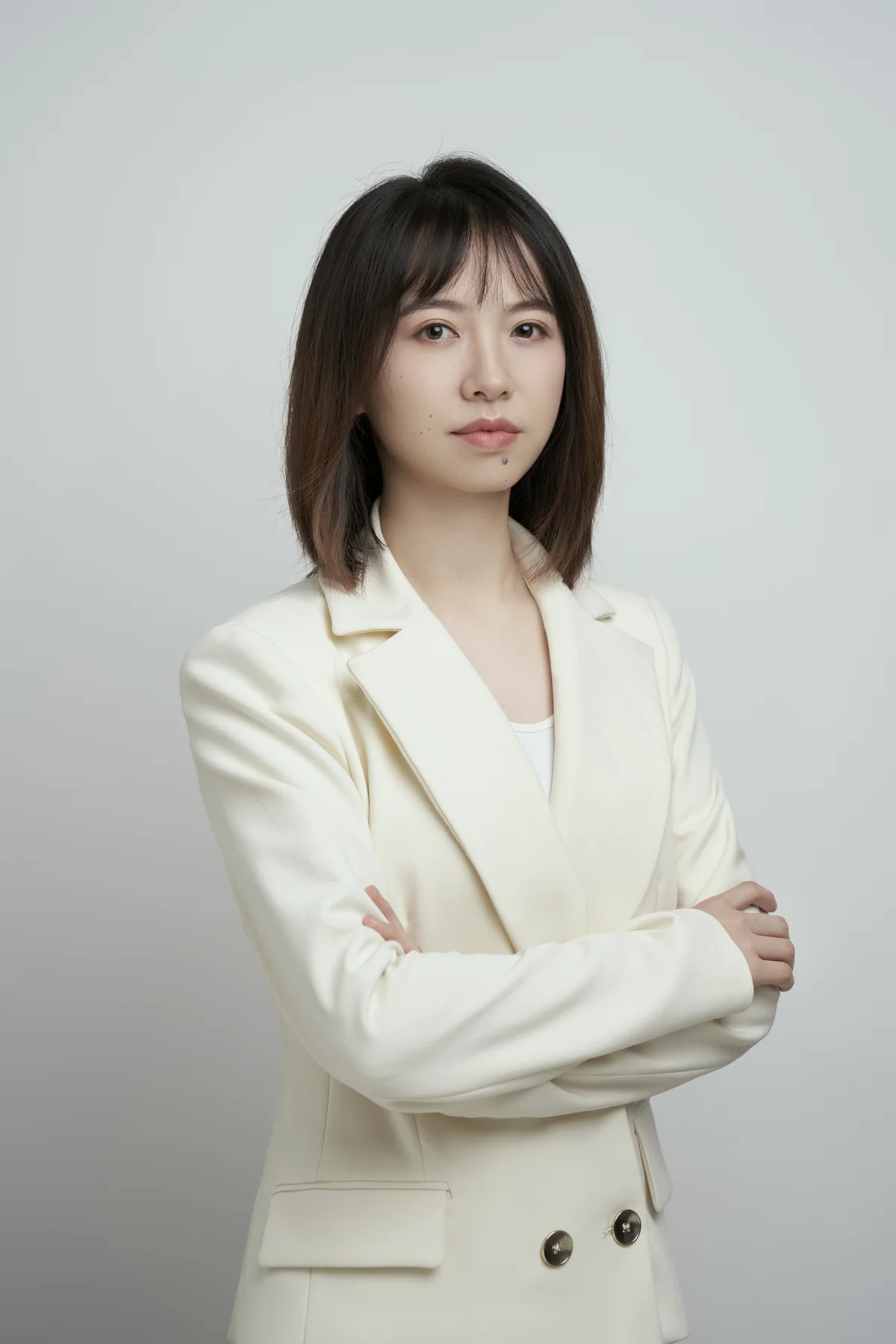 Coach Ellen 身着米白西装,双臂交叠站在浅灰背景前